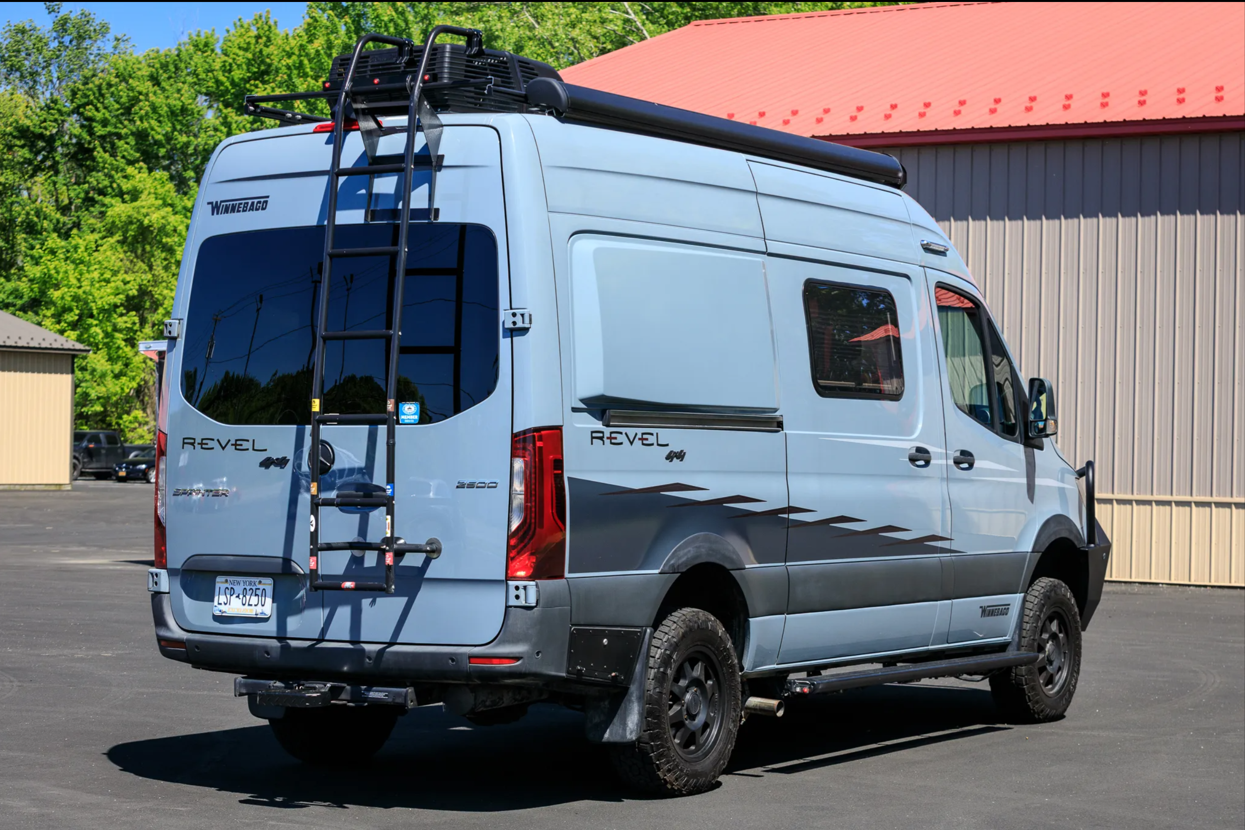 Rear quarter view — ladder, roof rack, and Revel 4×4 branding